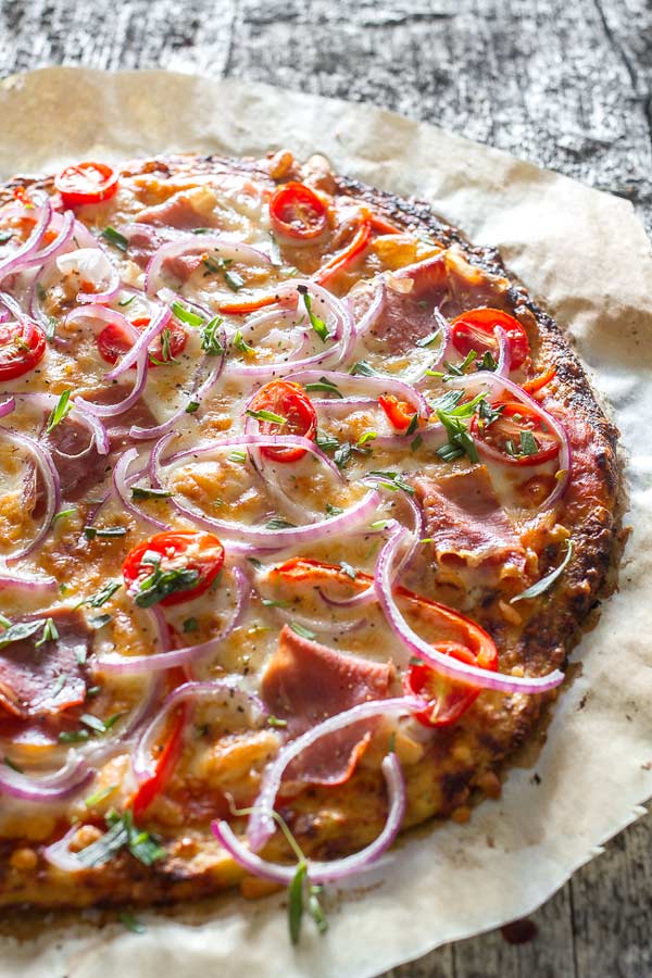 Delicious healthy pizza recipe featuring mozzarella cheese and prosciutto, on a delicious thin crust made from cauliflower sprinkled with fresh tarragon.